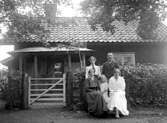 EN MAN MED TRE KVINNOR OCH ETT BARN FRAMFÖR ETT BOSTADSHUS.

Fotot taget i aug 1917.