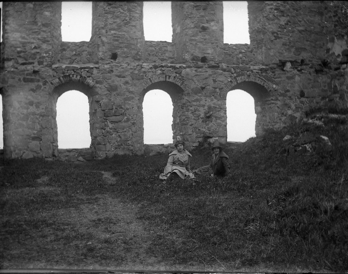 Anna Elisabet Karolina Rythén, Två unga kvinnar sitter på marken i Brahehus slottsruin. De bär kappa och hatt. Det är möjligen syskonen Anna-Lisa och Karin Rythén