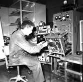 Varvet runt- en bildutställning
Televerkstaden 1965.\\Telemontören Lars-Erik Olsson trimmar 1965 en kortvågssändare på televerkstaden. För detta arbete behövdes en stor uppsättning instrument bl a oscilloskop, tongenerator och transistoriserad räknare.