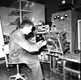 Varvet runt- en bildutställning
Televerkstaden 1965.\\Telemontören Lars-Erik Olsson trimmar 1965 en kortvågssändare på televerkstaden. För detta arbete behövdes en stor uppsättning instrument bl a oscilloskop, tongenerator och transistoriserad räknare.