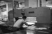 Man i arbete vid skärmaskin på pappersbruket Papyrus i Mölndal, hösten 1970. Renskärning av papper för att få exakta mått. Anställda på Papyrus kallade skärmaskinen 