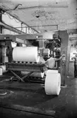 Man i arbete vid maskin på pappersbruket Papyrus i Mölndal, hösten 1970. Voldemar Mei. Klippmaskin 5, byggnad 10. Rullarna går igenom klippmaskinen och det kommer ut ark på pall.