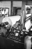 Män i arbete vid rullmaskin 5 på pappersbruket Papyrus i Mölndal, hösten 1970. Maskinen rullar ner en tambour till smårullar.