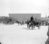 Stockholms slott med hästdroskor och en bil.