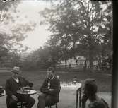 Två män i trädgård lyssnande på fonograf, Lillhärad, ca 1910.