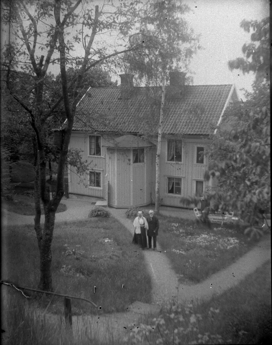 Unknown artist, The courtyard side of Bergsgatan 2 with a stairwell located. In the courtyard that has several gravel paths between lawns, an elderly couple, the owners, arm hook face the photographer.