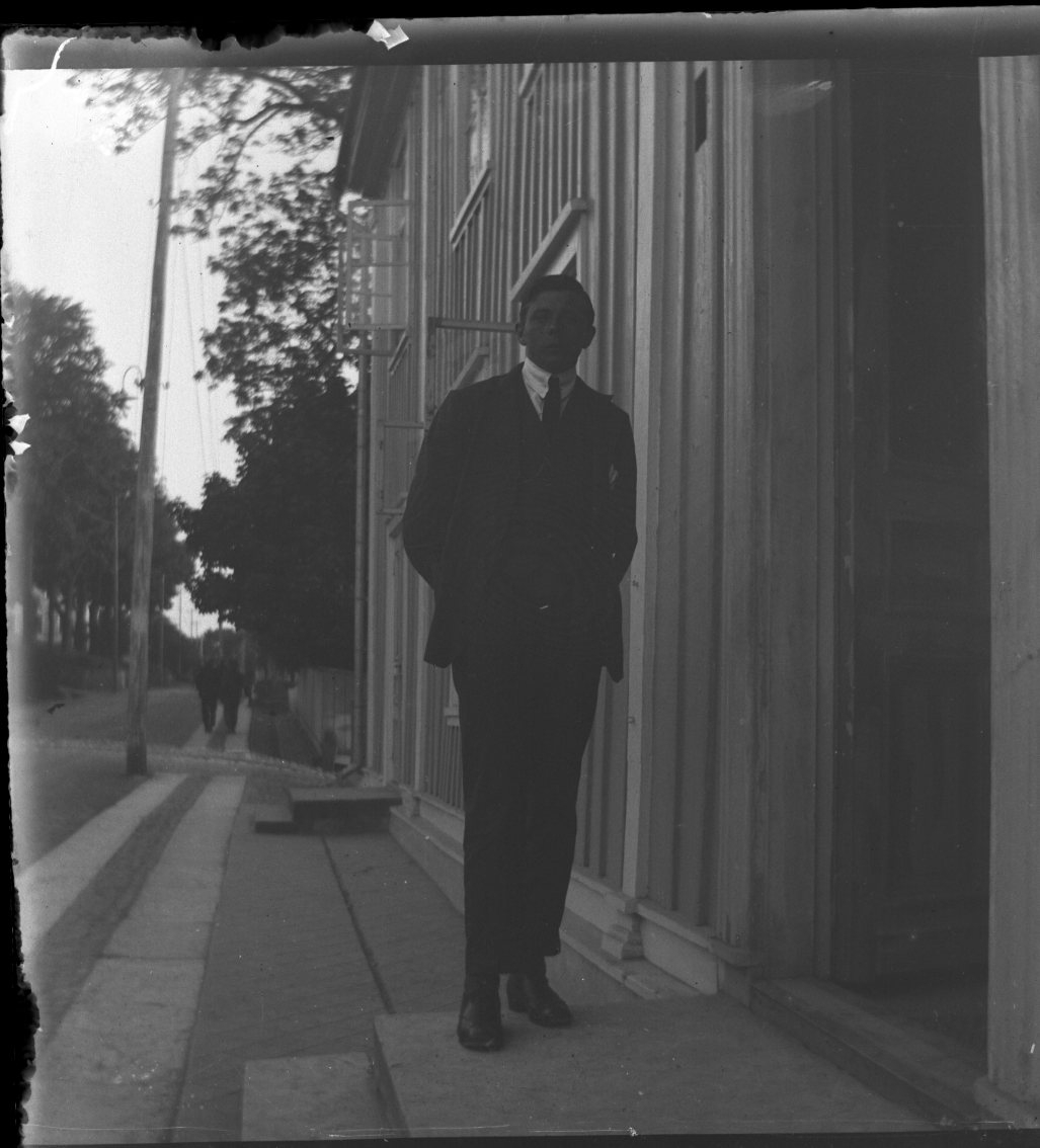 Unknown artist, An unknown young person faces the photographer outside the entrance to Hotell Brahe.