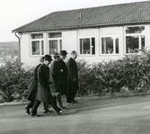 Fem män på väg till Kålleredsskolan (Brattåsskolan) år 1966. De är där i samband med Biskopsvisitationen. Från vänster: kyrkoherde Lennart Levén, (något skymd) komminister Gustaf Lindman, rektor Gunnar Hillerström, biskop Bo Giertz samt Ragnar Andersson från Skolstyrelsen.