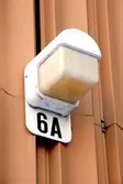Husnummer och ytterbelysning i kombination. Byggnadsdetalj från huset Bergmansgatan 6 i Mölndals Centrum. Fotografi taget den 26 februari 2018. Byggnadsdokumentation inför rivning.