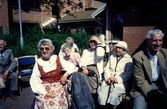 Midsommar utanför Brattåsgårdens äldreboende cirka 1986 - 1990. I folkdräkt ses Stina Svensson, kvinnan med solglasögon är Paula Carlsson (Arlas dotter), Arla Carlsson (i vit hatt) samt Oscar (efternamn saknas).