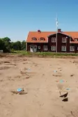 Stolphålen till ett långhus (hus B) från järnåldern markerademed blåfärgade papperstallrikar. Foto taget vid en arkeologisk undersökning i Gränna 2009.