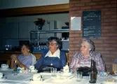 Tre kvinnor sitter till bords i Brattåsgårdens matsal, cirka 1990. Från vänster: Gunvor Johansson, Barbro Johansson och okänd.