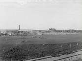 Varberg 1917. I förgrunden ett Järnvägsspår. Bortom beteshagarna syns en byggarbetsplats. Gunnebo bruks fabrik byggs.