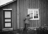 Nattfrieri. En man knackar på fönstret till stuga. Värmland, Mangskogs sn.