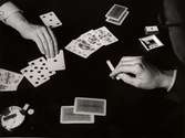 Spelkort på bord, hand med cigarett vilar mot bordet. Bridgeveckan oktober 1933.