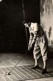 Golfutrustning NK (Nordiska Kompaniet) i Stockholm 1926. Manlig modell i golfkläder med golfklubba