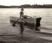 Kvinna i en enkel roddbåt. Träram klädd med ett vattenavvisande tygmaterial. Den 7 maj 1930