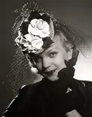 Hattmode, Nordiska Kompaniet 1941. Kvinnlig modell iförd liten rund hatt med flor och blomsterdekoration.