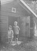 Porträtt av två små pojkar framför en stuga. Lima, Dalarna