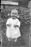 Porträtt av en liten leende flicka i trädgård. Lima, Dalarna.