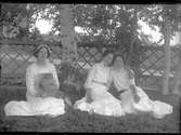 Tre unga kvinnor sittande på en gräsmatta. Lima, Dalarna.