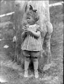 En liten flicka står vid en trädstam. Lima, Dalarna