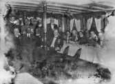 Första världskriget. Män och kvinnor i högtidsdräkt eller Röda Korsuniform ombord på ett fartyg.
