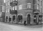 Karl Ask Färg kemikalie & tapetaffär i hörnet Nygatan-Österbrogatan. Herr Borgman står framför affären. Jordbrukarebanken.