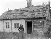 Lovisa Jansdotter framför sitt torp på gränsen mellan Litslena by och Hällby gård, Litslena socken, Uppland, 1910-tal