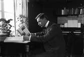 Josef Ärnström sitter vid skrivbordet och läser, Uppsala 1920-talet