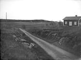 Landskapsvy med bostadshus och väg i Vittinge socken, Uppland i maj 1922