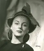 Porträtt av kvinna i hatt med rosett och flor, samt örhängen och brosch, från Rose Valois.