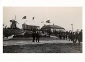Utställning. Hantverks- och industriutställningen i Varberg 1904. Utställningsområdet i kvarteret Lilla Kari med den för tillfället uppbyggda serveringspaviljongen i mitten. Paviljongen flyttades senare till gamla Påskberget. Bilden tagen mot öster. Till höger syns norra ordens huset (Folkets hus) där man hade utällning av Mejeri- och fiskeprodukter. Bilden tagen mot sydost.