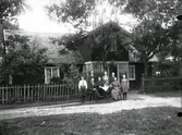 En samling personer (familj?) framföör ett hus i Brännilt, Krogsered socken.