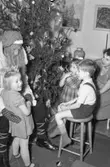Tre förväntansfulla barn och en kvinna tillsammans med tomten, december 1949