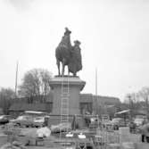 Dubbelstatyn på Kungstorget i Uddevalla används som stöd för stege vid exponering av marknadsvaror, 23 maj 1958