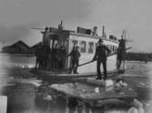 Män tar sig fram bland isflaken med färjan mellan Koön och Marstrand