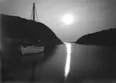 Juli 1924. Månskensfotografi med fiskebåt och farledsfyr, den södra smala delen av sundet Havstenssund.