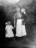 Justin Olsson med ett barn i famnen och ett som hon håller i handen, 1915