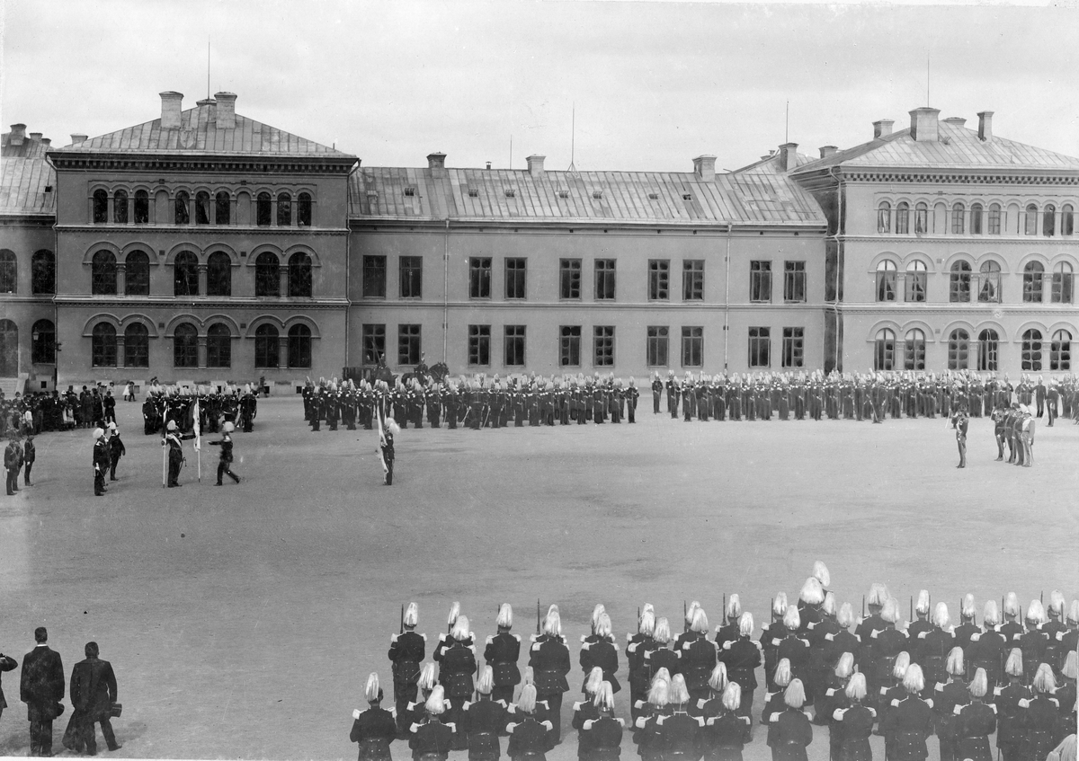 Lars Larsson, Kung Oscar II delar ut fanor åt Göta livgarde I 2 utanför regementet på Storgatan i Stockholm. Civila åskådare ser på i bakgrunden.