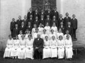 Konfirmandgrupp vid Simtuna kyrka, Uppland, sannolikt 26 juni 1916. I mitten kyrkoherde August Hylander (1852-1935).