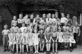 Flickor och pojkar sittande och stående framför Centralskolans port i Mölndal år 1950. Med på fotot är givaren Margit Hellström (f. Willumsen).