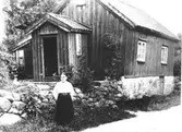 Annestorp i Lindome på 1920-talet. Maria utanför sin stuga. (anteckning av H.B). Maria var rörelsehindrad och arbetade på fabriken. Hon var född 1846.