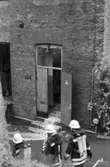Soab-branden i Stora Götafors den 4 juni 1986. Tre brandmän står utanför en öppen dörr till fastigheten.
