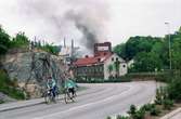 Soab-branden i Stora Götafors den 4 juni 1986. Två personer som cyklar utanför Papyrus mur.