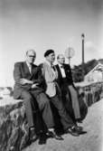 Tre män som sitter på en stenmur, 1949-1950. Mannen längst till höger var sysslomannen vid Lackarebäckshemmet, Nils Gustafsson (senare Wadell).