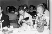 Luciafest på Eisers fabrik 1965. Personal runt kaffebord som lyssnar till sång och gitarrspel framförda av två kvinnor.