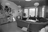 Ett allrum där tre män sitter i en soffa. Dokumentation av Sagåsens flyktingförläggning, 1992.