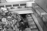 Paketsorteringsmaskin å huvudpostkontoret i Kyoto, Japan. 
Foton 21/12 1962.  Från grovsorteringen.  Påläggning av paket på
bricktransportören.  Obs!  Sorterarens plats är längre fram på bandet.