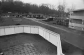 Dokumentation av Sagåsens flyktingförläggning 1992. Utsikt från en inhägnad utomhus-lekplats mot fastigheter i bakgrunden.